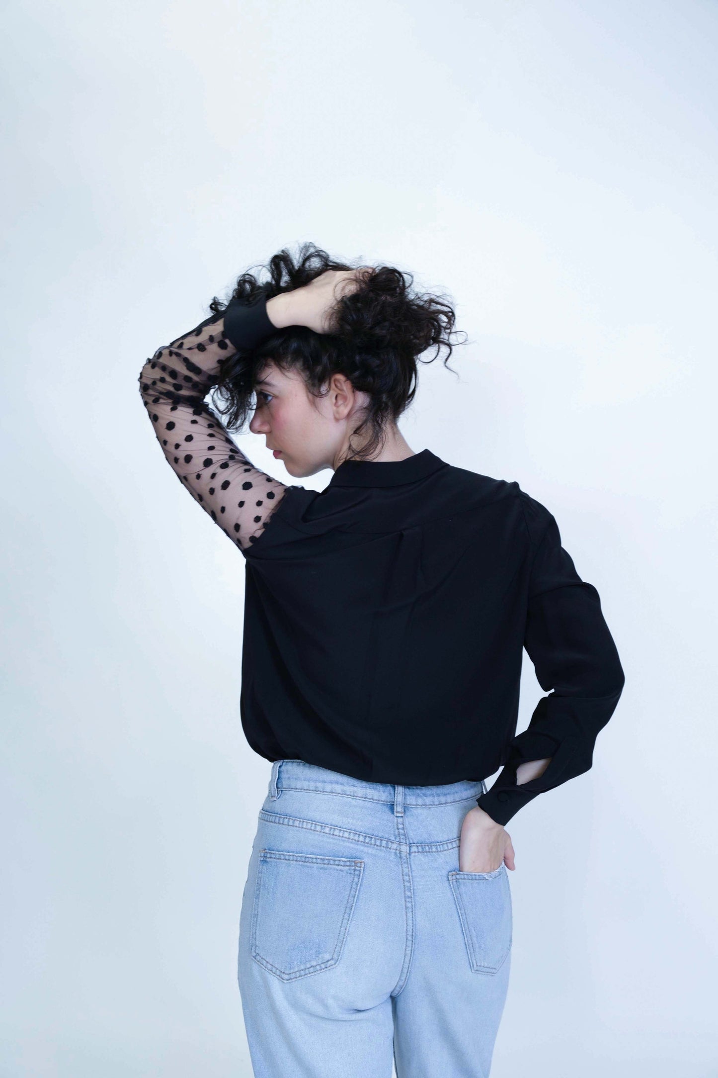 Chemisier asymétrique pour femme réalisé à la main, en soie noire et manche gauche en tulle brodé, vue de dos, mouvement.