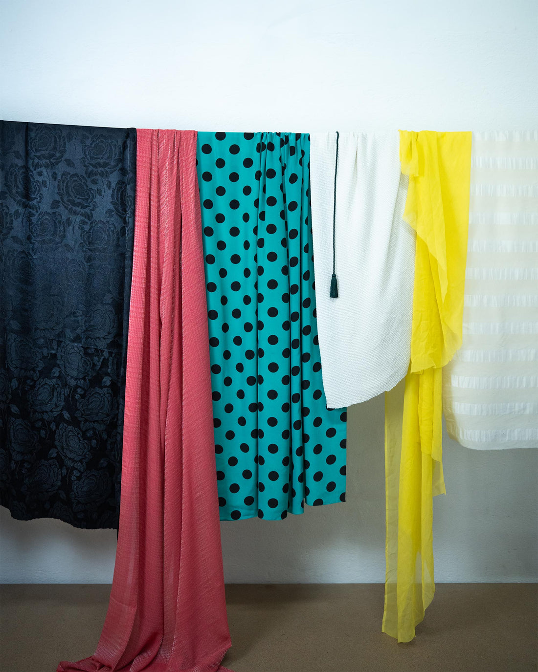 Plusieurs tissus colorés suspendus côte à côte dans l’atelier