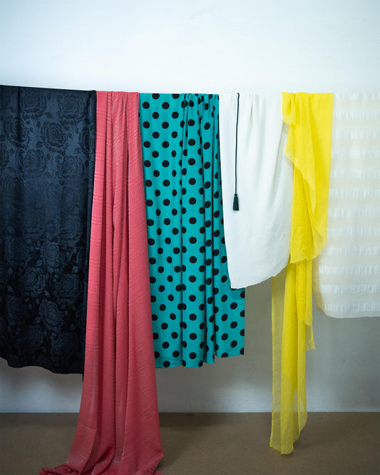 Plusieurs tissus colorés suspendus côte à côte dans l’atelier