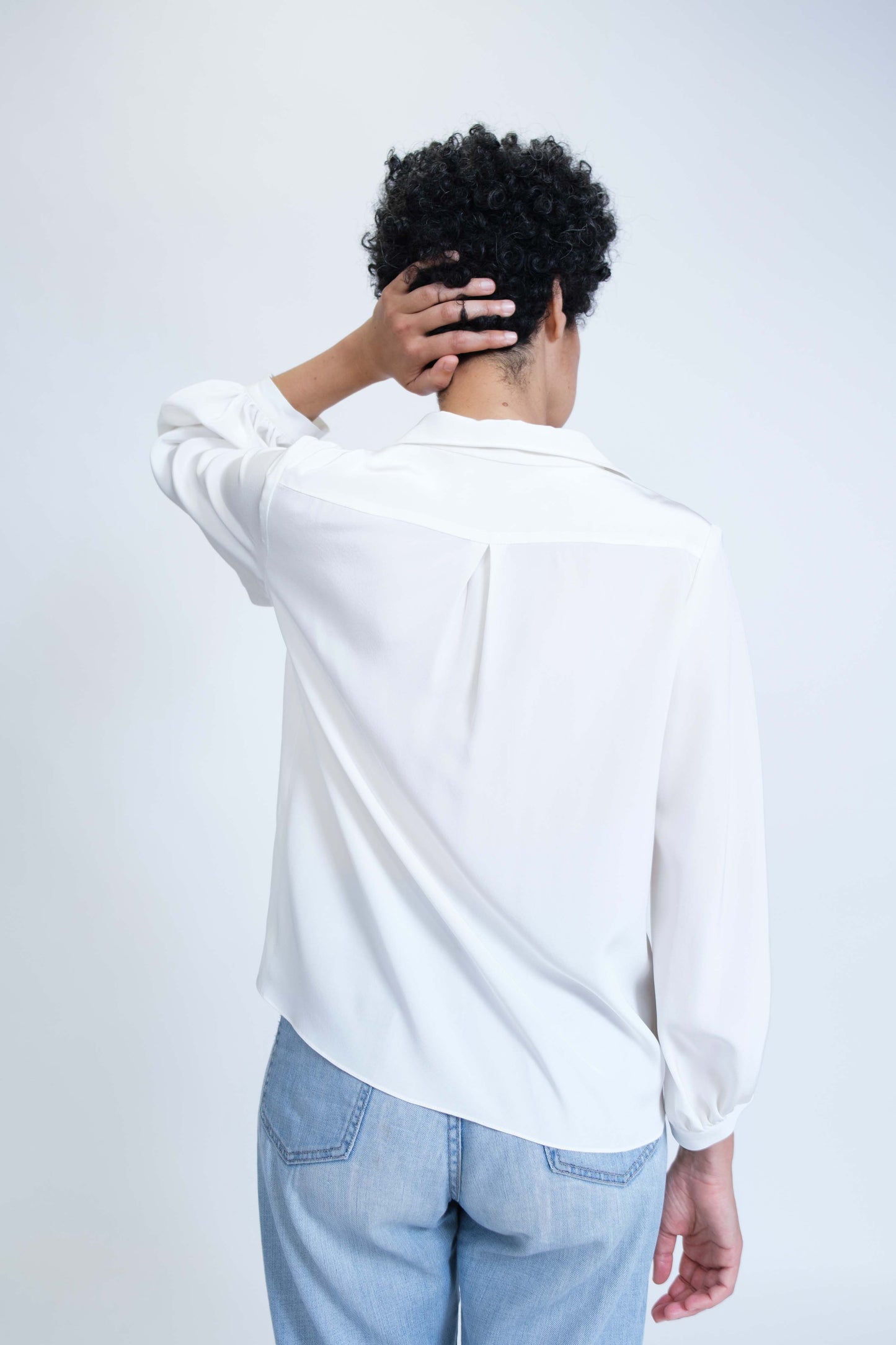 Chemise femme réalisée à la main en crêpe de soie blanc et ses boutons coeur rouges, vue de dos, détail empiècement et pli creux dos.