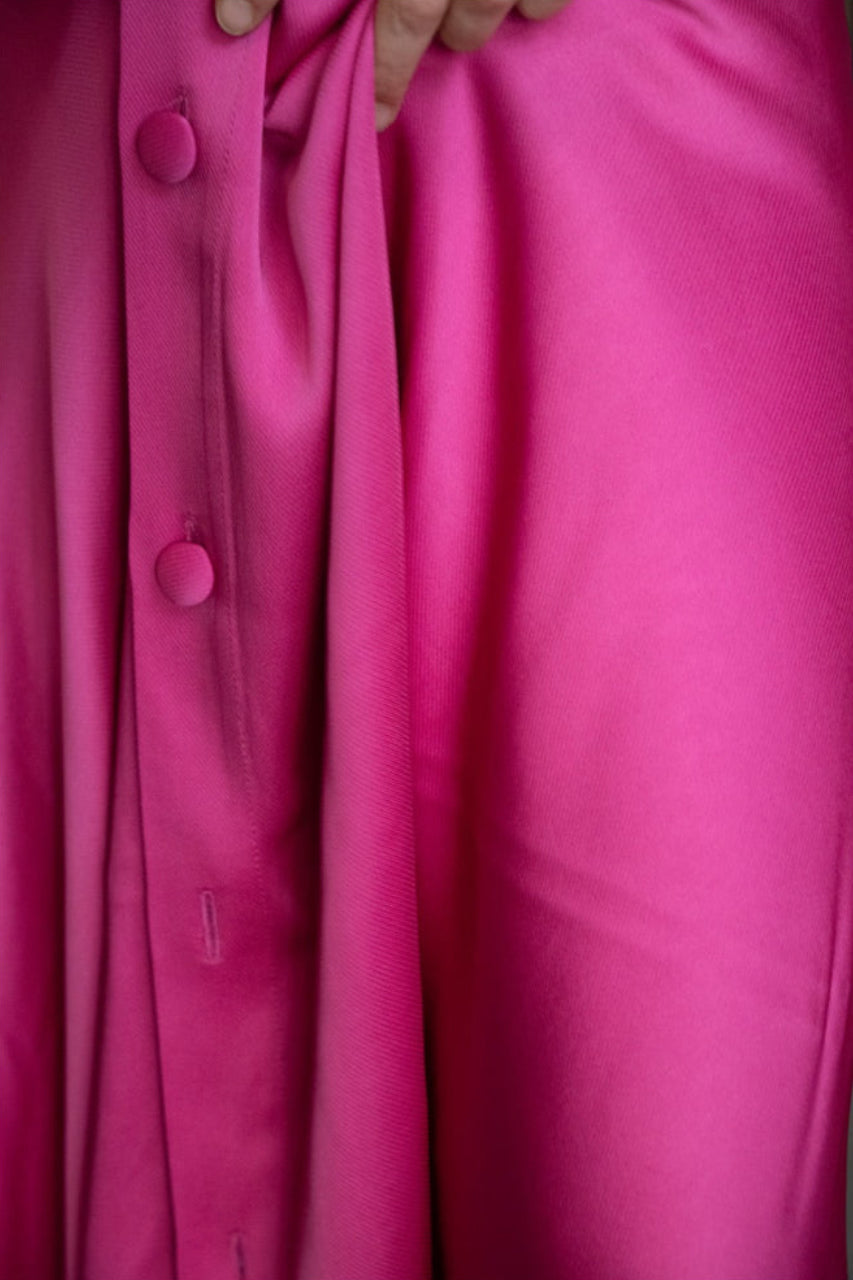 Vue rapprochée d'un drapé de jupe en satin de viscose lourd, couleur rose intense. 