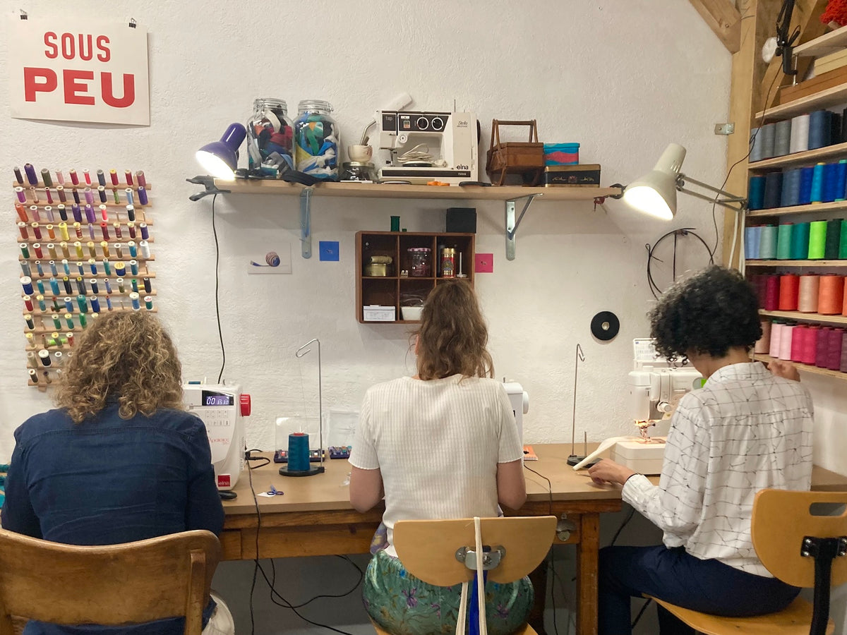Trois élèves travaillent à leur machine pendant un cours de couture à Marseille.